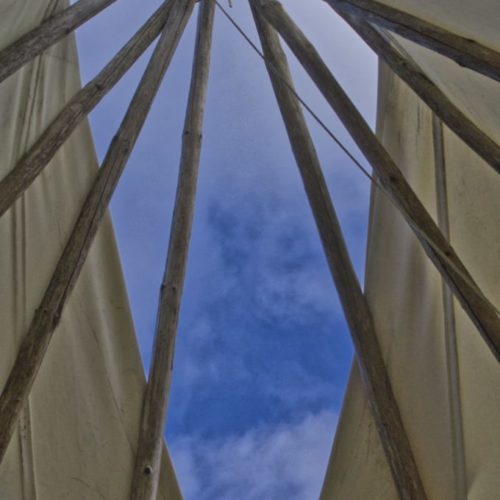 Inside of Tipi with canvas. Blue sky and clouds in background